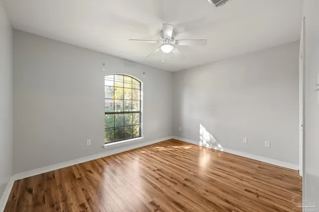 a view of empty room with wooden floor and fan