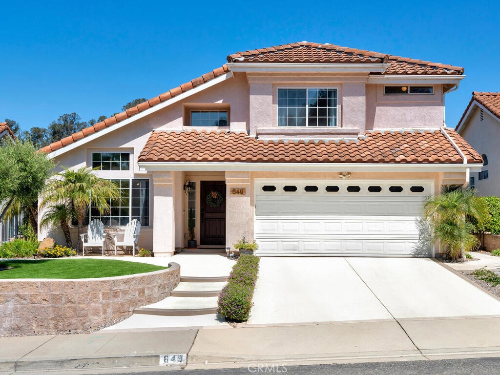 a front view of a house with a yard and potted plants
