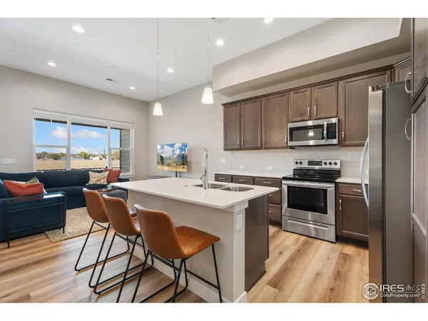 a kitchen with stainless steel appliances a stove a sink a microwave a refrigerator and cabinets