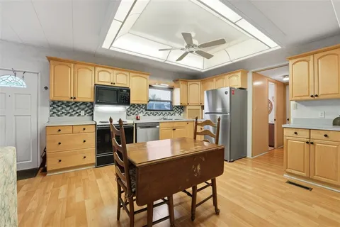 a kitchen with stainless steel appliances a stove a refrigerator cabinets and a dining table