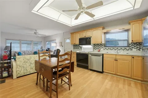 a open kitchen with stainless steel appliances kitchen island granite countertop a stove a sink a dining table and chairs with wooden floor