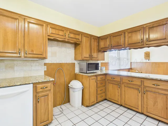 a kitchen with granite countertop a sink window and cabinets