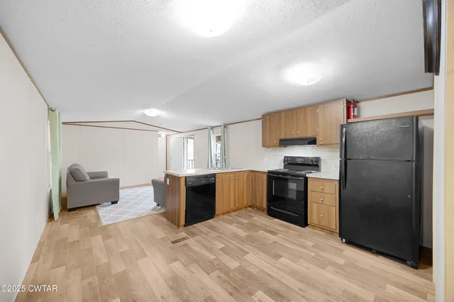 a kitchen with stainless steel appliances kitchen island granite countertop a refrigerator stove top oven and sink