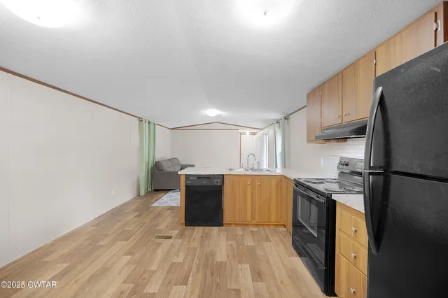 a kitchen with stainless steel appliances granite countertop a refrigerator a stove a sink dishwasher and a refrigerator with wooden floor