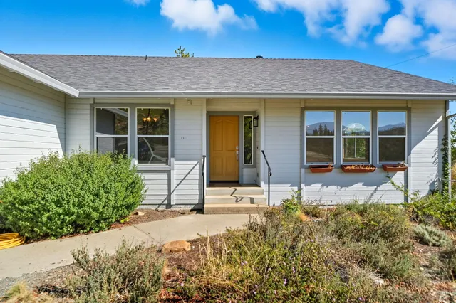 a backyard of a house with table and chairs under an umbrella