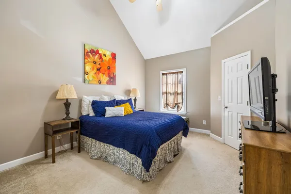 a bedroom with a bed table flat screen tv and a window