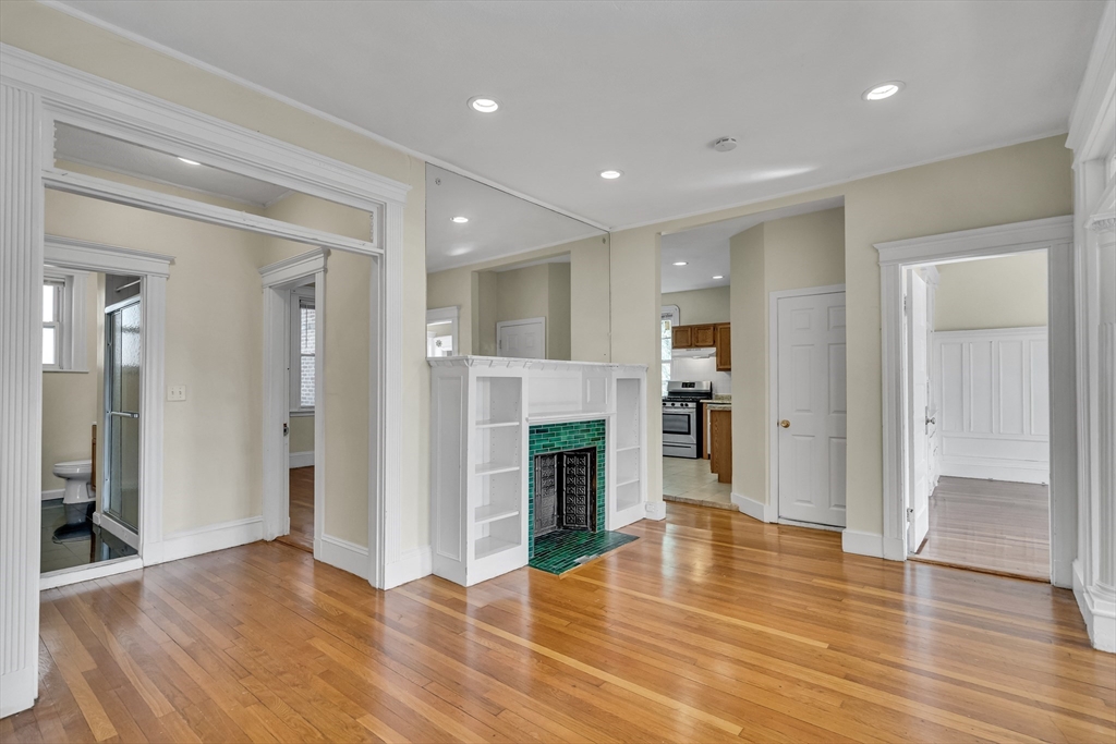 41 Orkney Road Boston, MA 02135 - Photo 6 of 28 an empty room with wooden floor and a kitchen space