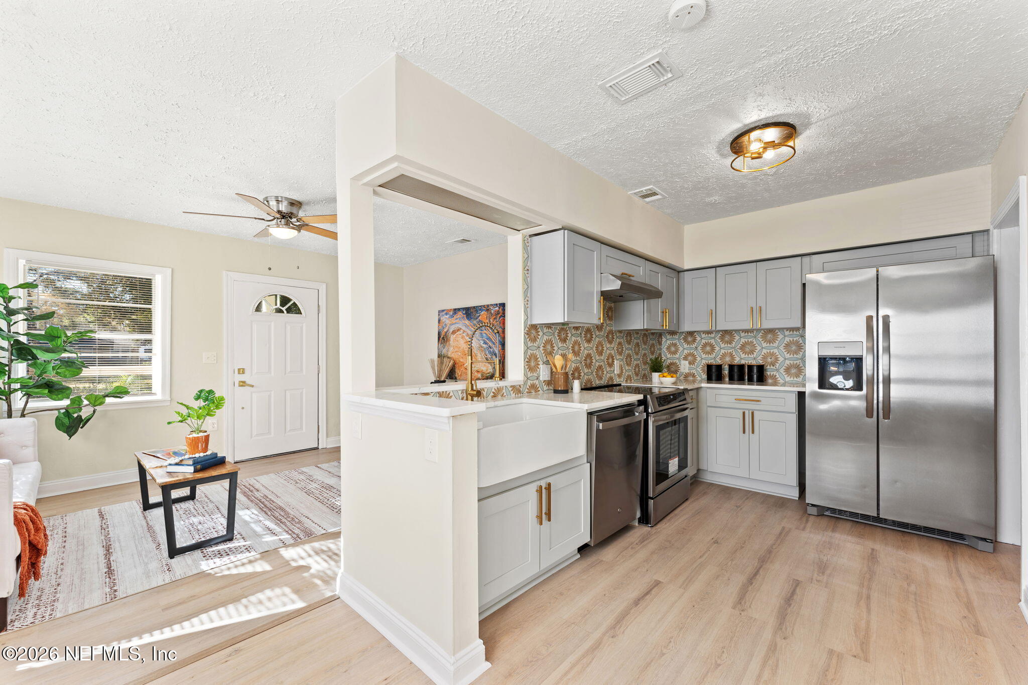 4517 Delta Avenue Jacksonville, FL 32205 - Photo 9 of 25 a kitchen with a refrigerator a microwave a stove and white cabinets with wooden floor