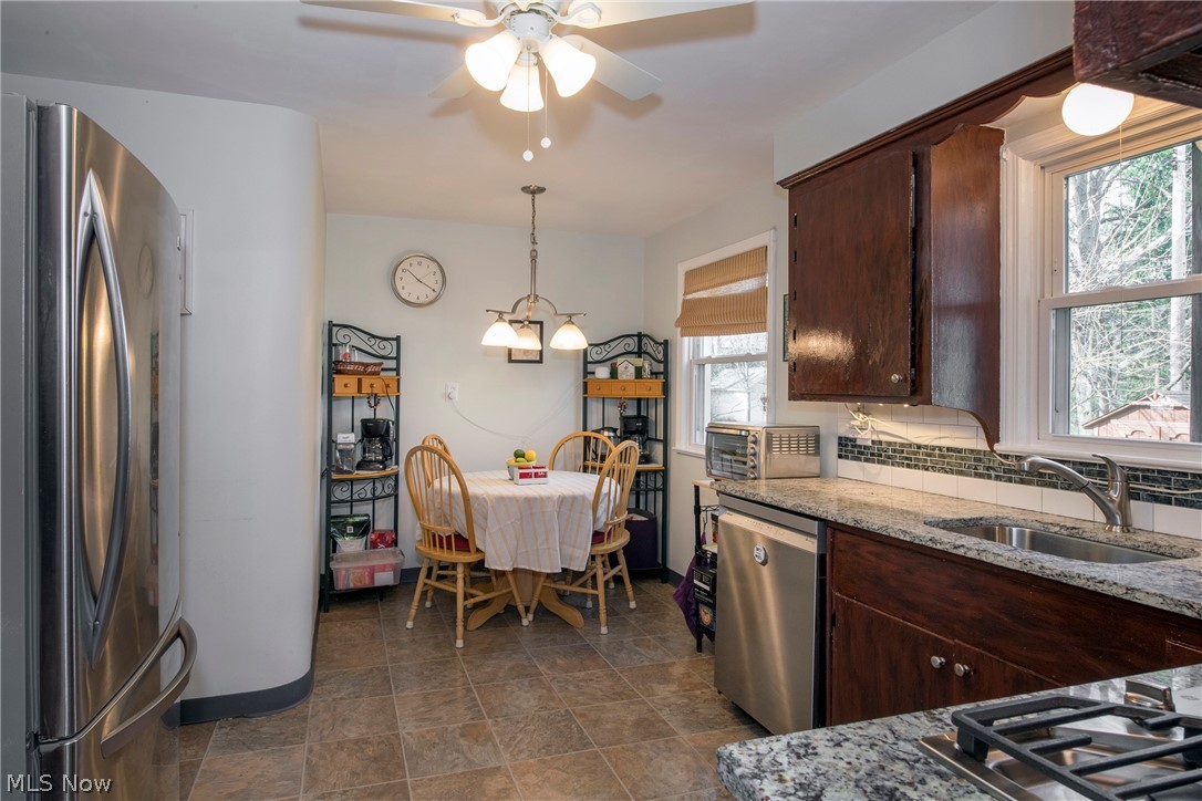 1170 Roland Road Lyndhurst, OH 44124 - Photo 10 of 36 Kitchen with tasteful backsplash, ceiling fan with notable chandelier, appliances with stainless steel finishes, light stone counters, and hanging light fixtures