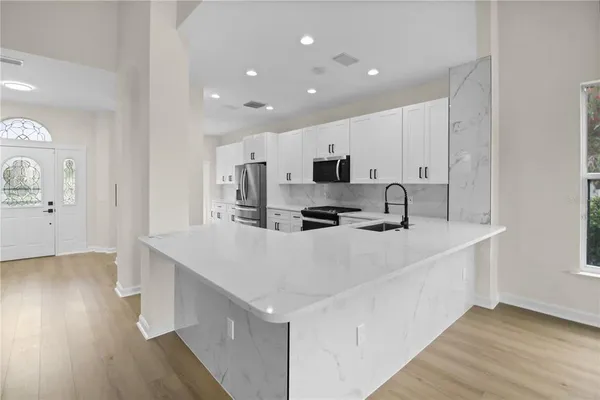 a large white kitchen with wooden floor and a sink