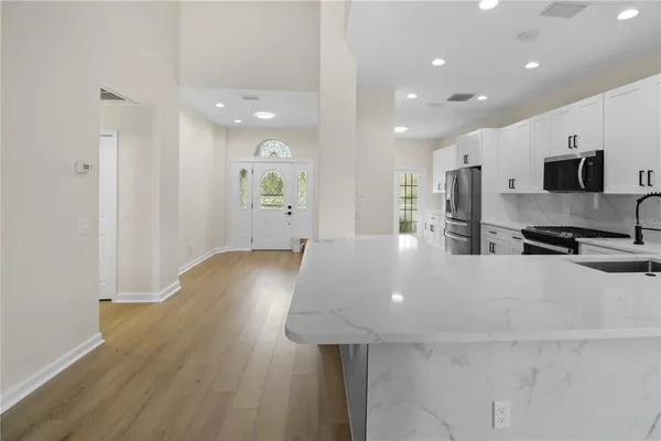 a large kitchen with stainless steel appliances a large counter top a stove and a refrigerator