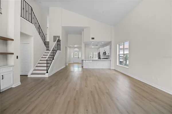 an empty room with wooden floor fan and windows