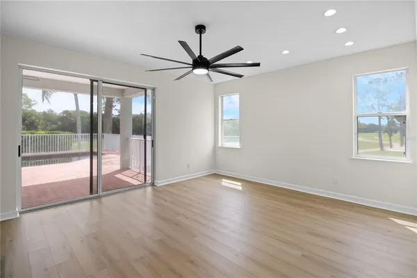 a view of an empty room with wooden floor and a ceiling fan