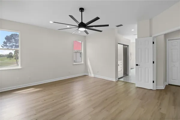 a view of empty room with wooden floor and fan