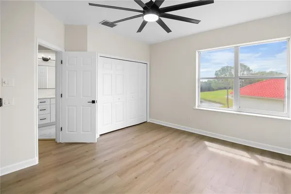 an empty room with wooden floor fan and windows