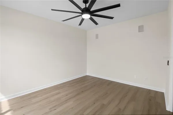 an empty room with wooden floor fan and windows