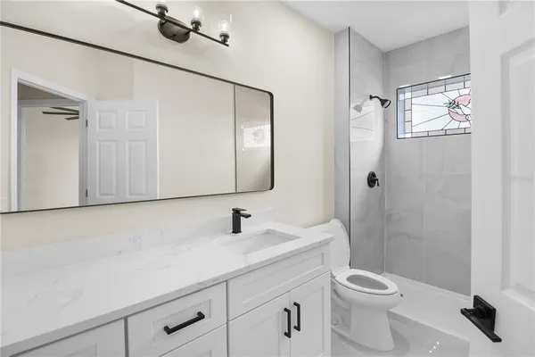 a bathroom with a toilet sink vanity and mirror