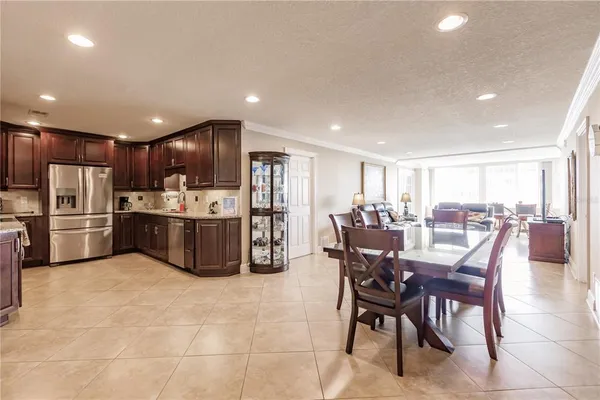 a kitchen with stainless steel appliances a refrigerator a sink a stove a dining table and chairs