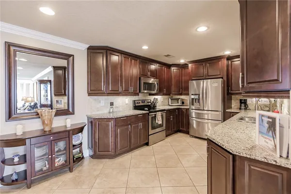 a kitchen with stainless steel appliances granite countertop a sink stove refrigerator and cabinets