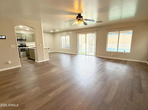 a view of an empty room with window and wooden floor
