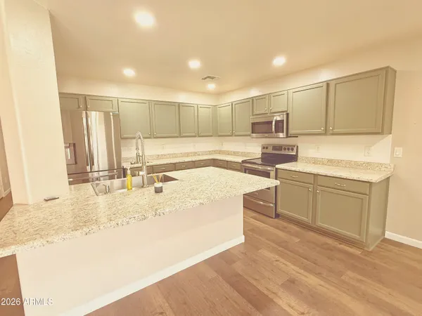 a kitchen with a sink a stove a refrigerator and white cabinets