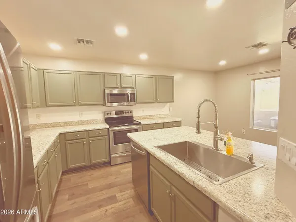 a kitchen with kitchen island granite countertop a sink a counter top space appliances and cabinets
