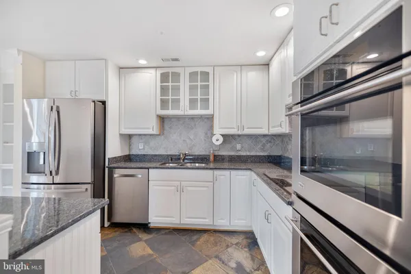 a kitchen with stainless steel appliances granite countertop a refrigerator and a stove top oven