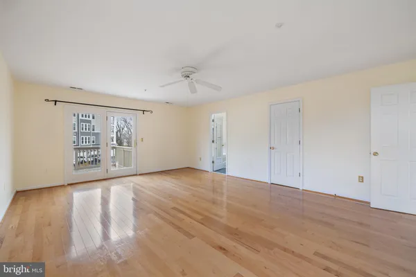 a view of empty room with wooden floor and fan