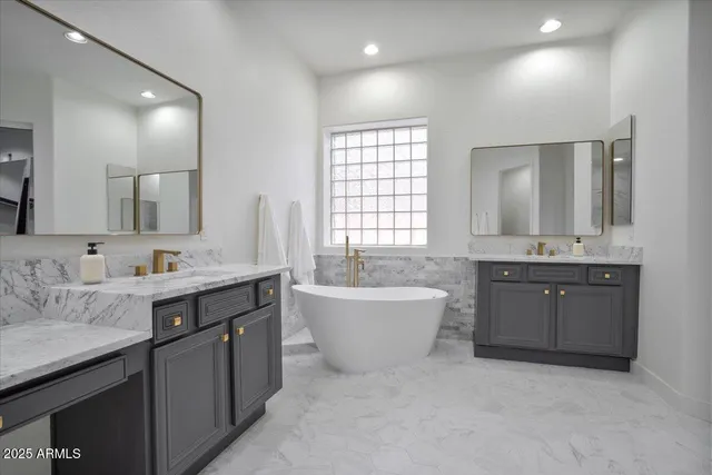 a spacious bathroom with a granite countertop double vanity sink a mirror and a bathtub