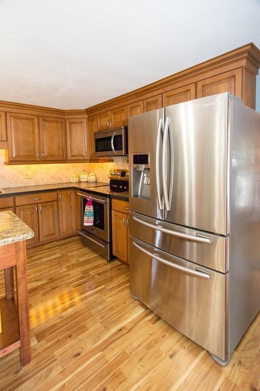 59 Warren Road Framingham, MA 01702 - Photo 7 of 25 a kitchen with stainless steel appliances granite countertop a refrigerator a sink dishwasher a dining table and chairs with wooden floor