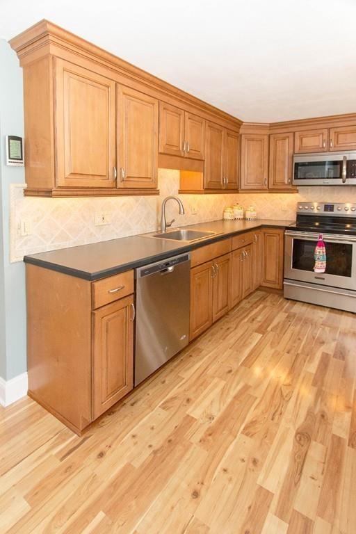 59 Warren Road Framingham, MA 01702 - Photo 8 of 25 a kitchen with stainless steel appliances granite countertop a stove a sink and a microwave