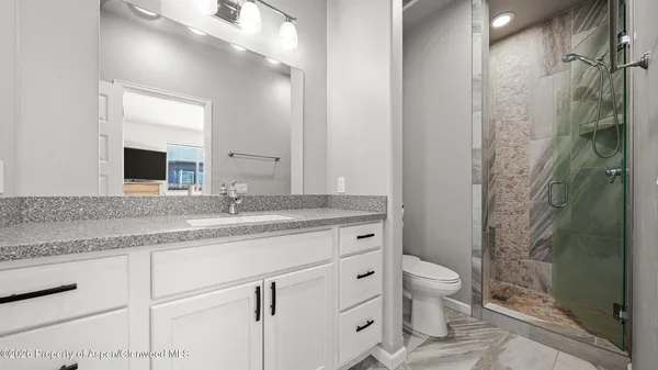 a bathroom with a granite countertop sink toilet and shower