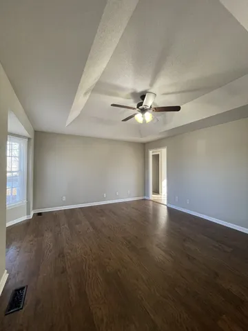 a view of an empty room with window and wooden floor