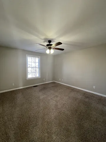 an empty room with windows and chandelier fan