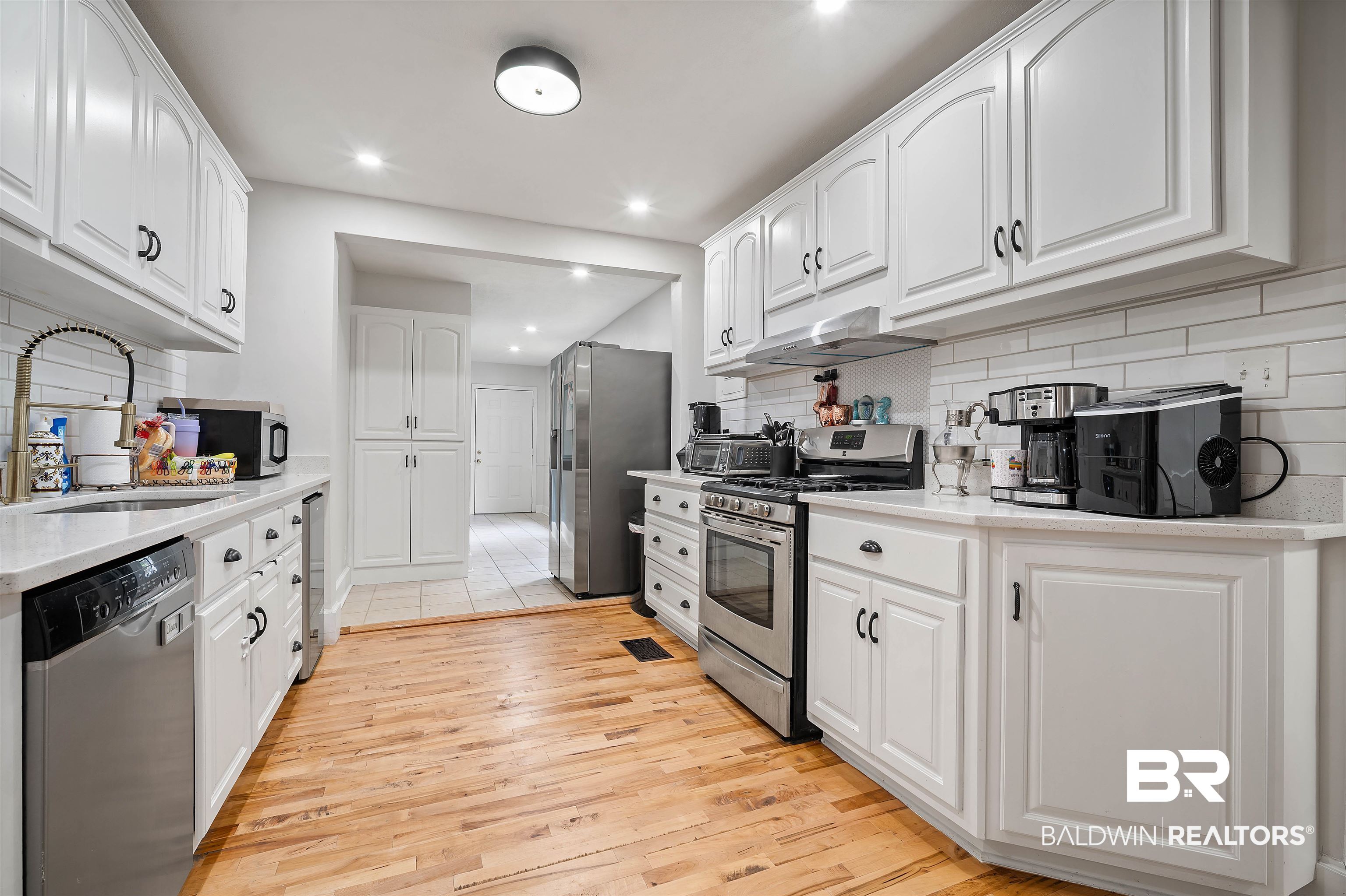 103 Emogene Place Mobile, AL 36606 - Photo 10 of 32 Kitchen featuring stainless steel appliances, white cabinets, decorative backsplash, light stone countertops, and recessed lighting