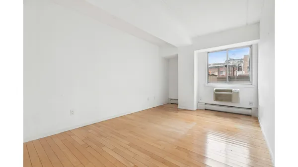 a view of a big room with wooden floor and a kitchen