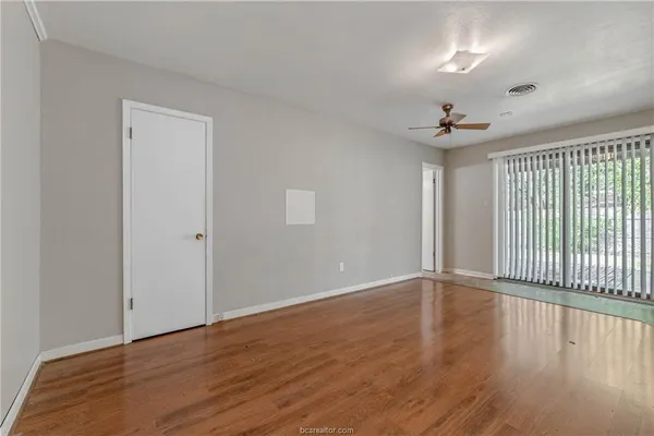 a view of an empty room with wooden floor and a window