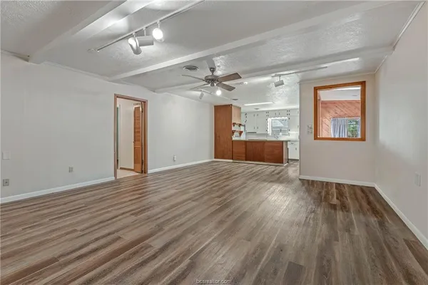a view of a livingroom with wooden floor a ceiling fan and windows