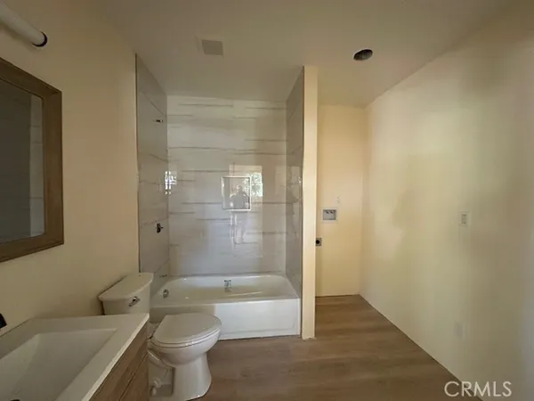 a bathroom with a granite countertop bathtub shower sink vanity and toilet