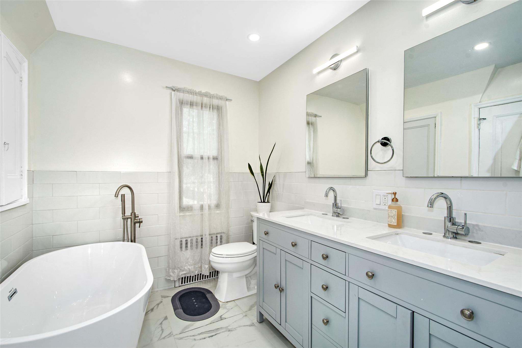 2 Byworth Road New Rochelle, NY 10804 - Photo 20 of 31 Full bath featuring tile walls, double vanity, a freestanding tub, marble finish floors, and toilet