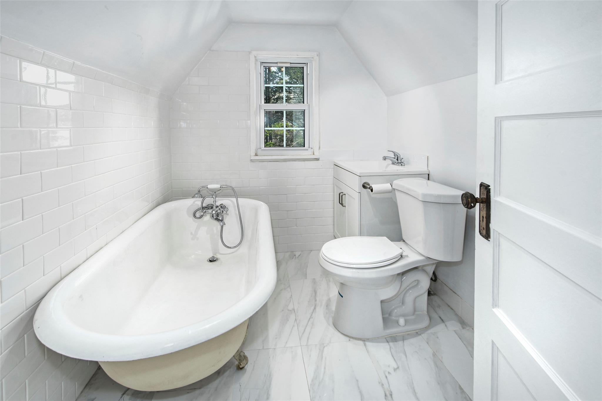 2 Byworth Road New Rochelle, NY 10804 - Photo 26 of 31 Bathroom featuring a freestanding bath, toilet, tile walls, marble finish floors, and vaulted ceiling