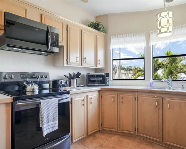 a kitchen with stainless steel appliances granite countertop a refrigerator a sink a stove and white cabinets