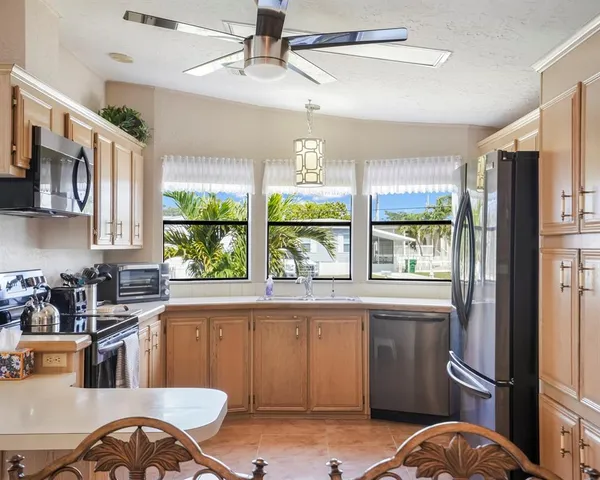 a kitchen with stainless steel appliances granite countertop a refrigerator a sink a stove and white cabinets