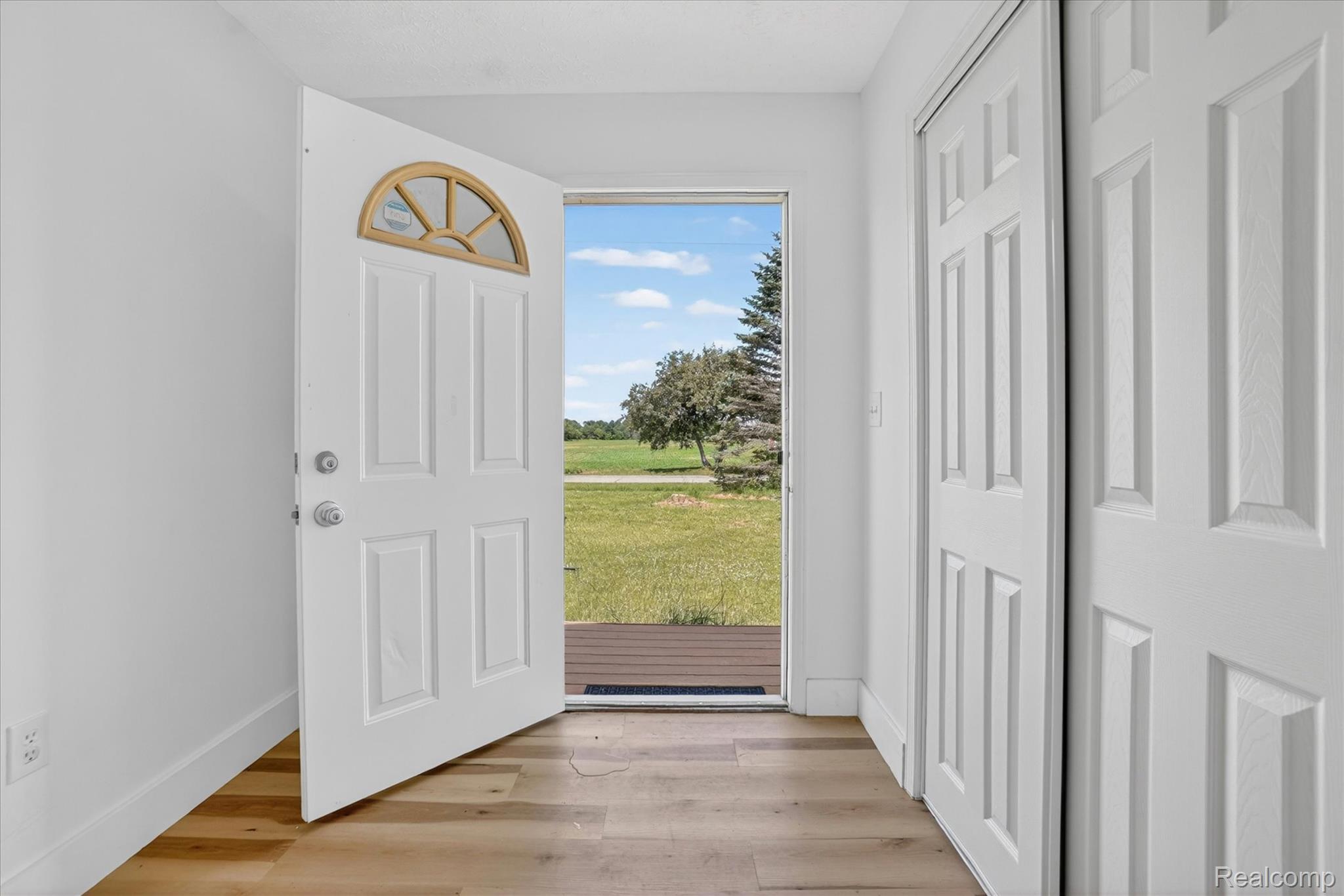 1400 North Every Road Mason, MI 48854 - Photo 2 of 33 Entryway with wood-finish flooring, white paneled doors, and a front door featuring a decorative arched window
