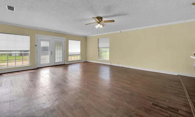 an empty room with wooden floor and windows