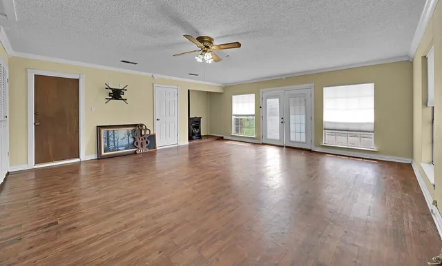 an empty room with wooden floor chandelier and windows