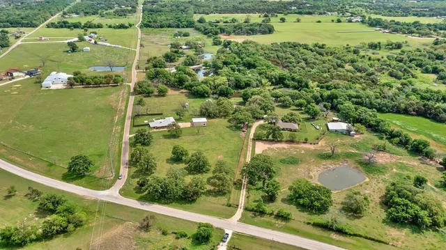 an aerial view of residential houses with outdoor space and trees