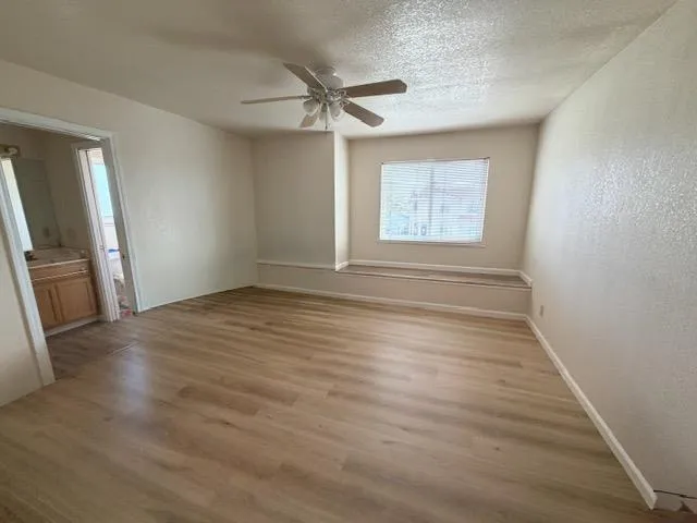 an empty room with wooden floor fan and windows