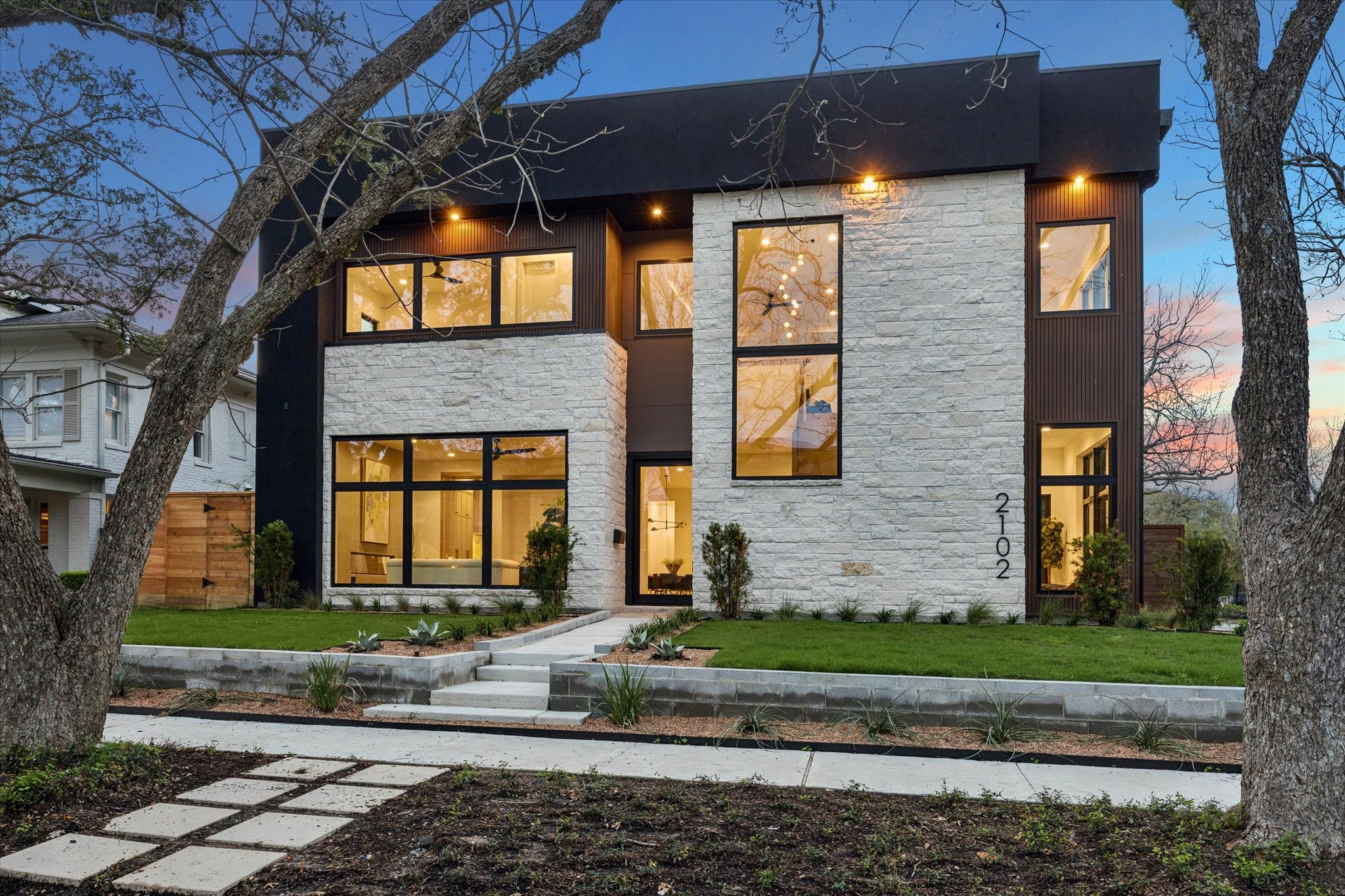 Bold & Modern two-story new construction home with a sleek design, featuring large windows that offer beautiful views of the tree lined street.  The exterior is a mix of stone, stucco and newtech wood.