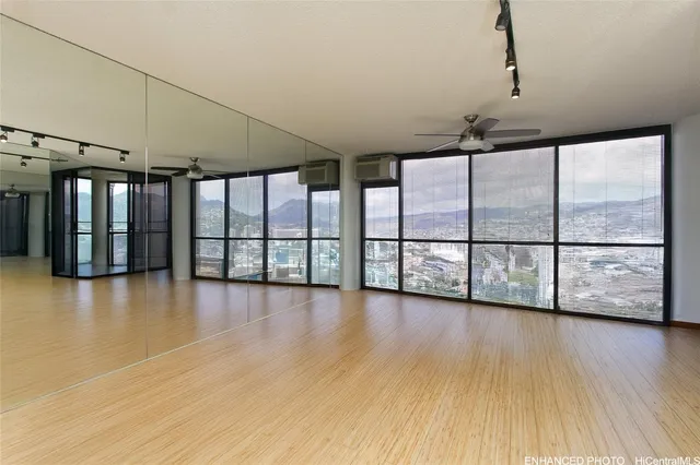 a view of an empty room with wooden floor and windows